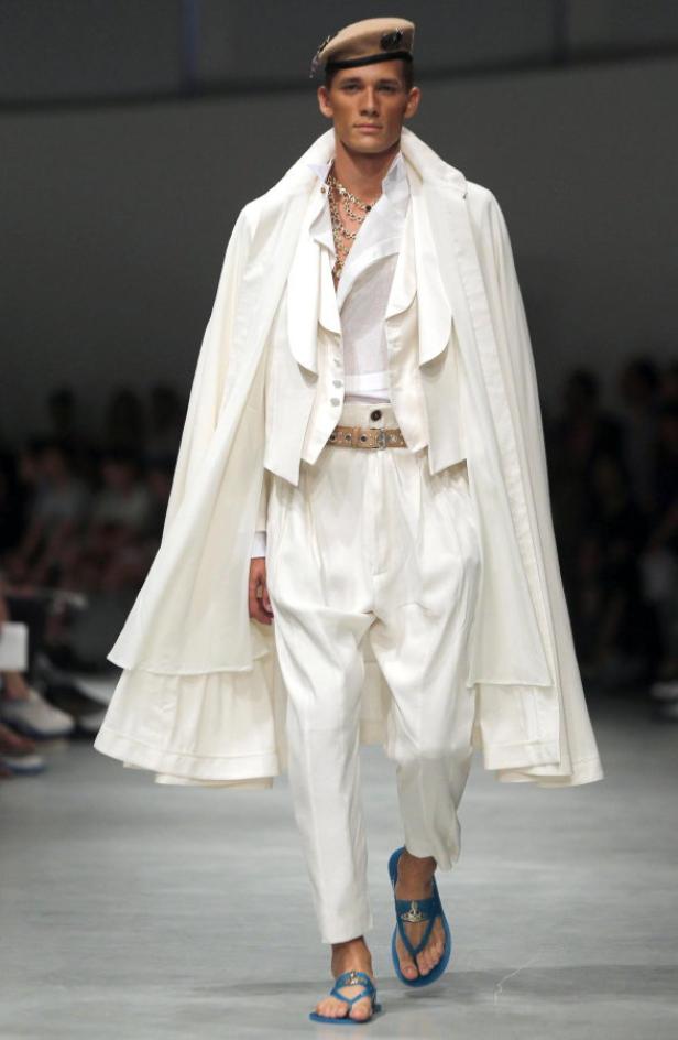 Ein Mann in einem weißen Anzug und Sandalen auf einem Laufsteg.