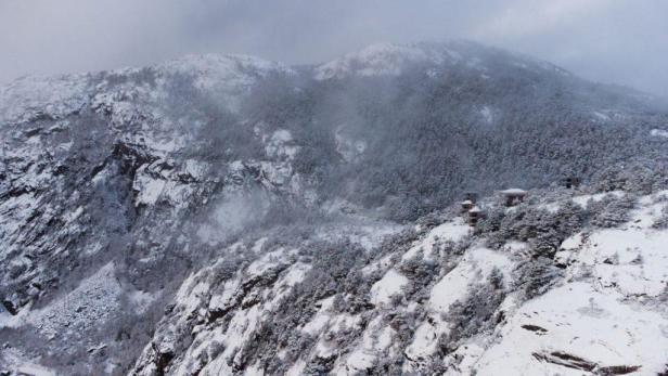 Verschneite Berge mit einigen kleinen Hütten an einem Hang.
