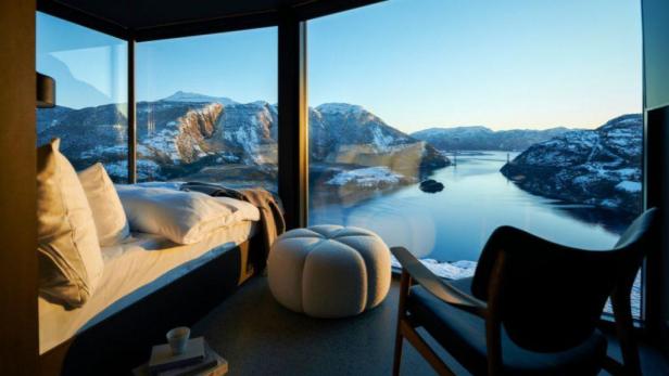 Blick aus einem Hotelzimmer auf einen Fjord und schneebedeckte Berge.