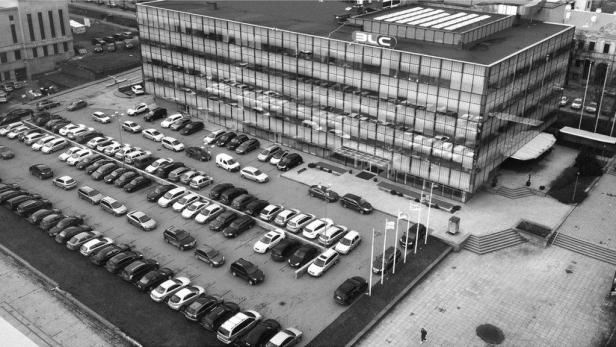 Das BLC-Bürogebäude in Kaunas mit einem vollen Parkplatz im Vordergrund.