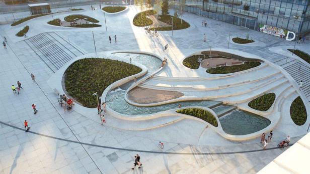 Ein belebter Stadtplatz mit Wasserspielen und Grünflächen in Kaunas, Litauen.