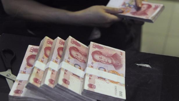 Mehrere Bündel chinesischer Yuan-Banknoten liegen auf einem Tisch.
