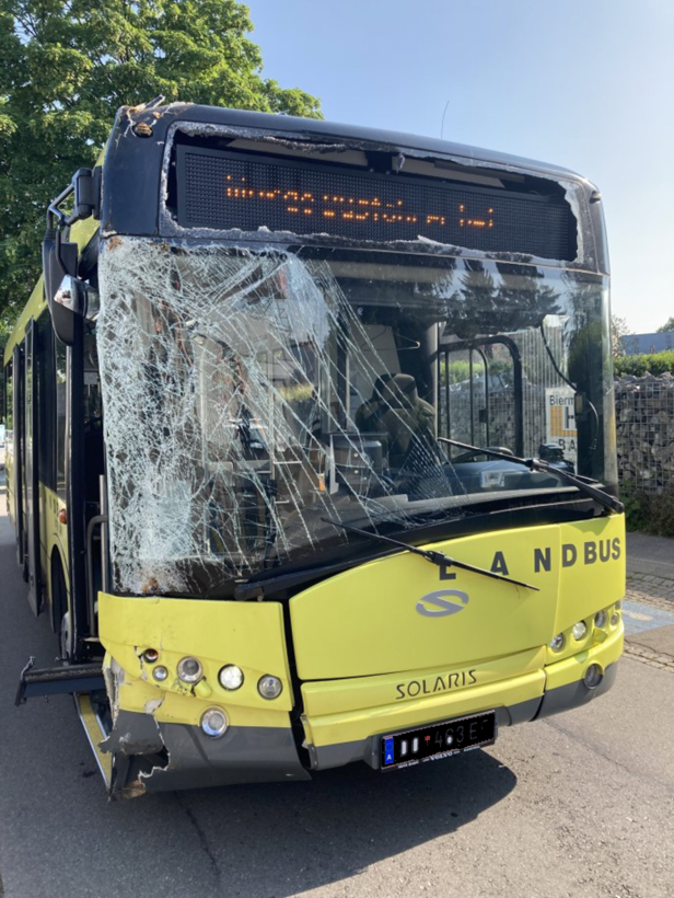 Ein gelber Linienbus mit eingeschlagener Windschutzscheibe und beschädigter Front steht auf der Straße.