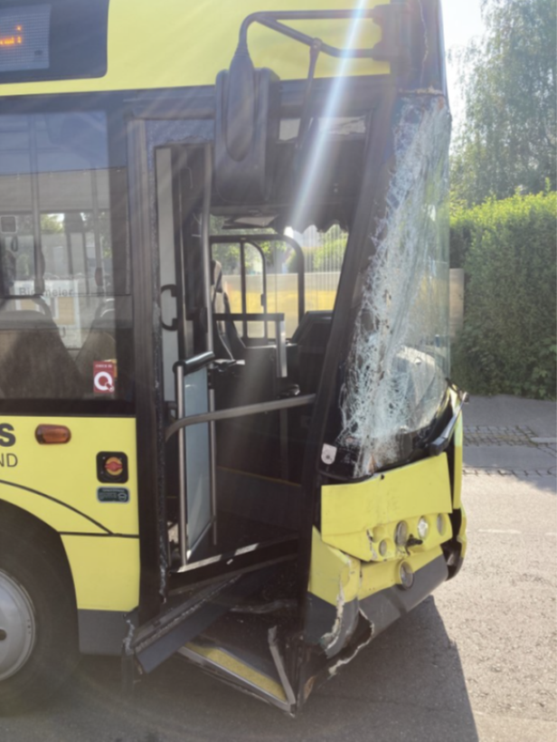 Ein gelber Bus mit einer zerstörten Windschutzscheibe und beschädigter Karosserie.