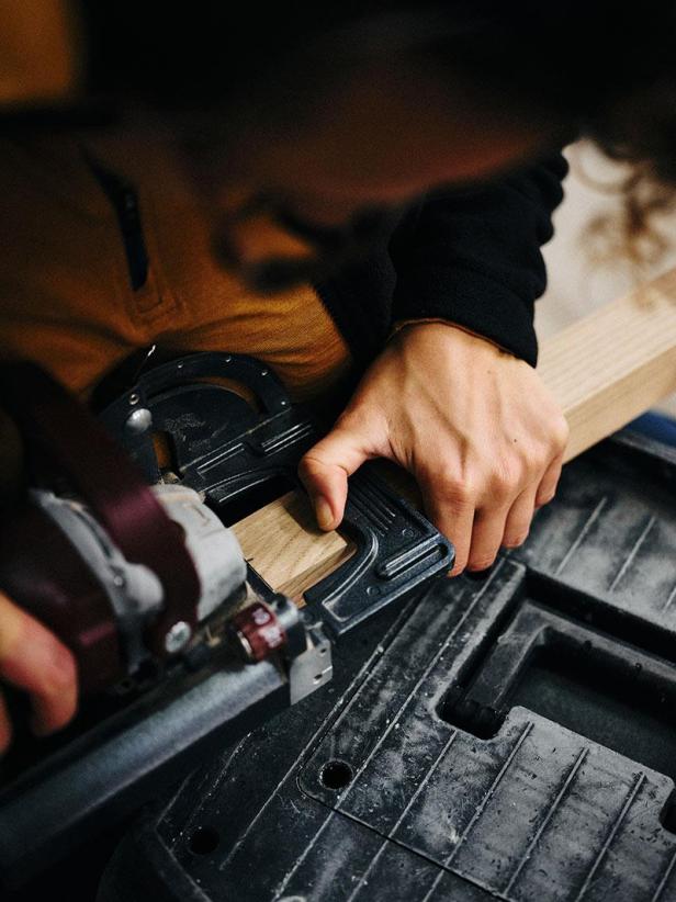 Eine Person bearbeitet ein Holzstück mit einem Werkzeug.
