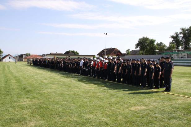 Eine lange Reihe von Feuerwehrleuten steht auf einem grünen Feld.