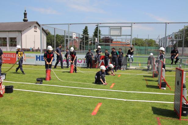 Jugendliche nehmen an einem Feuerwehrwettbewerb im Freien teil.