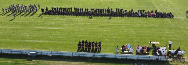 Eine große Gruppe von Menschen versammelt sich auf einem grünen Feld.