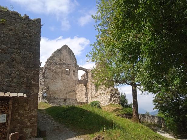 Die Ruine einer alten Burg auf einem grünen Hügel unter blauem Himmel.