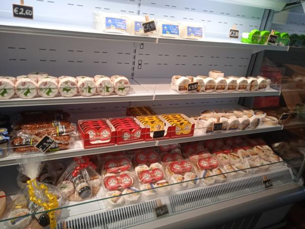 Eine Auslage mit verschiedenen Käsesorten und Wurstwaren in einem Kühlregal.