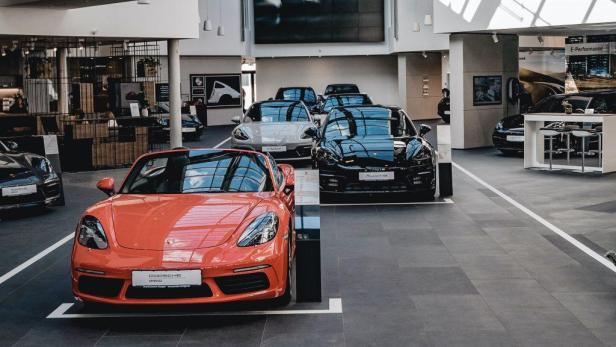 Ein roter Porsche steht in einem Ausstellungsraum, umgeben von anderen Porsche-Modellen.