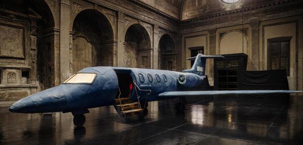 Ein blaues Flugzeugmodell steht in einem kunstvoll verzierten Raum.