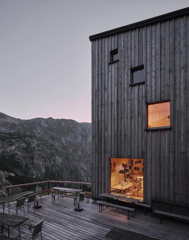 Die Voisthaler Hütte, ein Holzgebäude in den Bergen, mit Terrasse und Blick ins Innere.