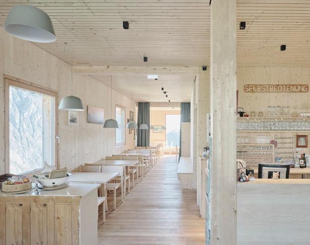 Innenansicht eines hellen Gastraums mit Holztäfelung und Blick auf die Berge.