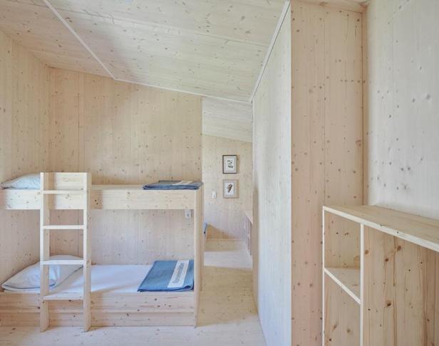 Ein Zimmer mit einem hölzernen Etagenbett und hellen Holzvertäfelungen.