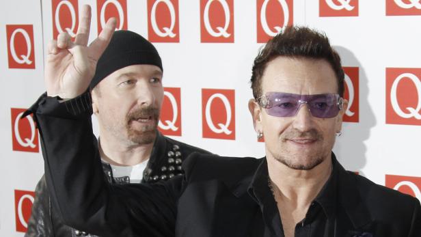 Bono und The Edge von U2 posieren auf einem roten Teppich.