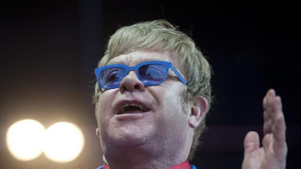 Elton John mit blauer Brille während eines Auftritts.