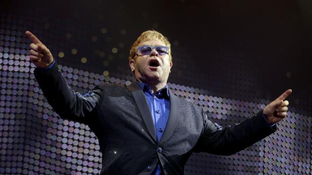 Elton John gestikuliert während eines Auftritts auf der Bühne.