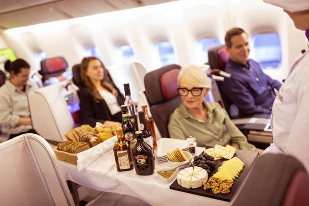 Passagiere genießen Käse, Brot und Getränke in der Business Class eines Flugzeugs.