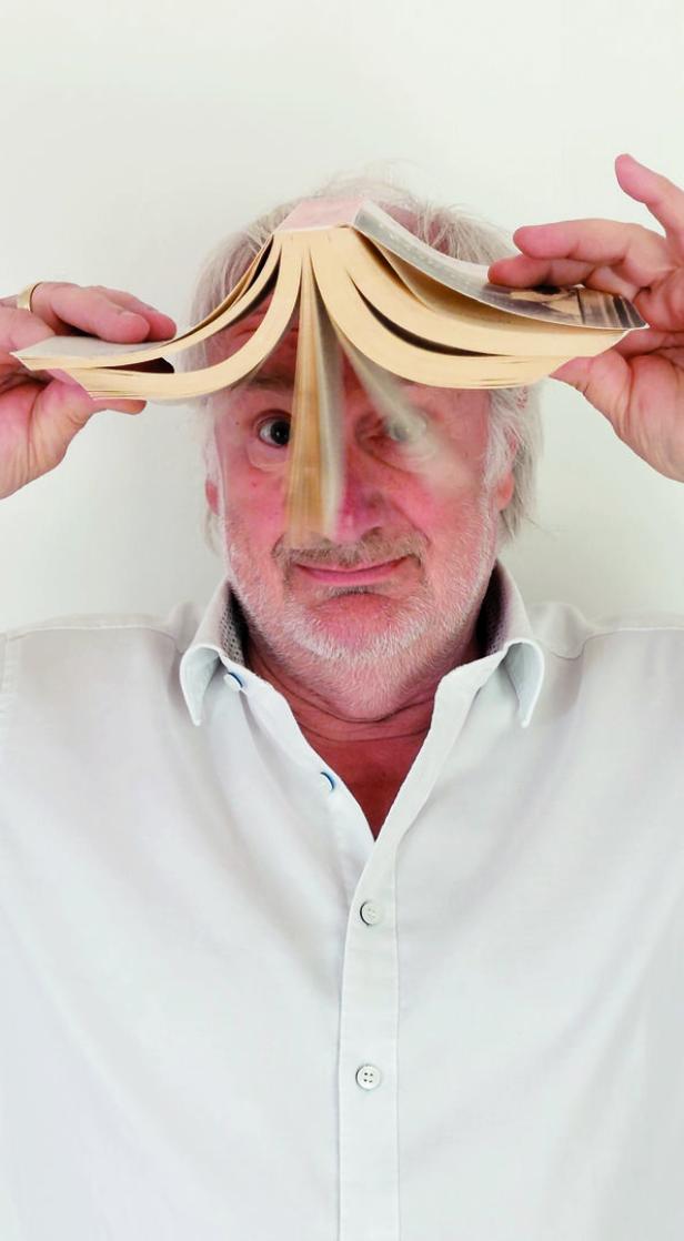 Ein Mann hält ein aufgeschlagenes Buch vor sein Gesicht.