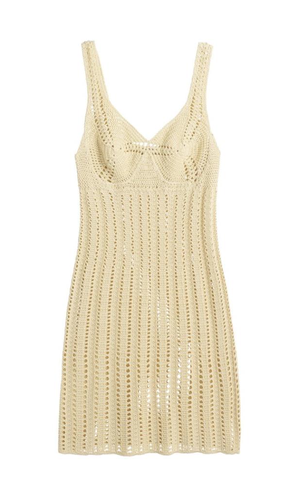 Ein cremefarbenes, gehäkeltes Minikleid mit Trägern vor einem weißen Hintergrund.