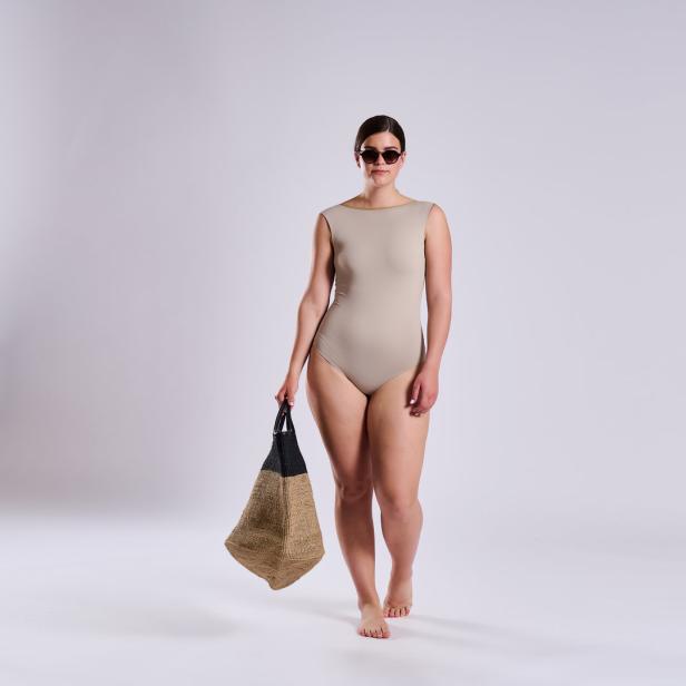Eine Frau mit Sonnenbrille und Badeanzug trägt eine Strandtasche.