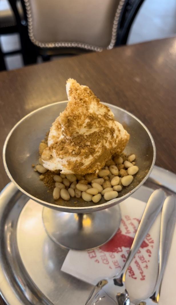 Ein Dessert mit Eis, Pinienkernen und Streuseln in einer silbernen Schale.