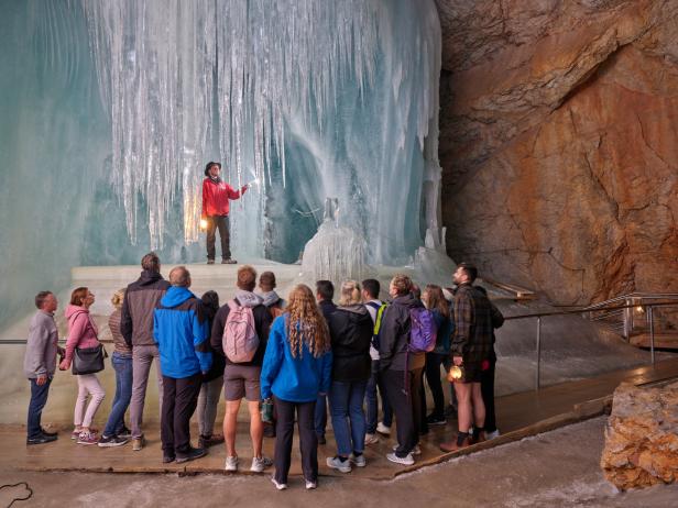 Eine Gruppe von Menschen besichtigt eine Eishöhle mit einem Führer.