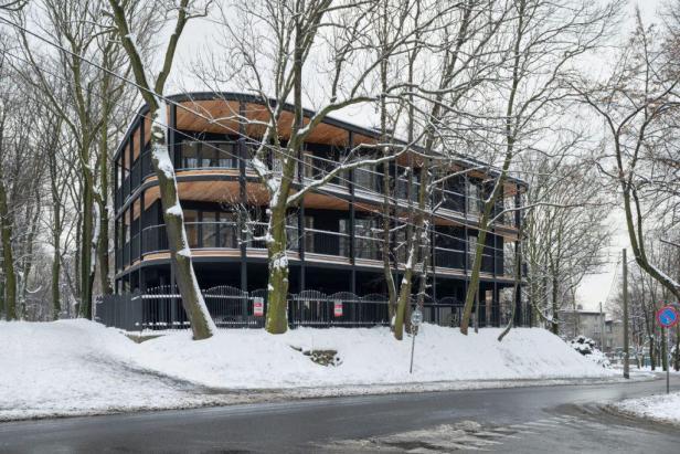 Eine moderne Villa mit mehreren Etagen im Winter, umgeben von Bäumen und Schnee.