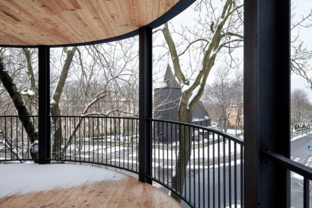 Blick von einem schneebedeckten Balkon auf eine dunkle Kirche im Winter.