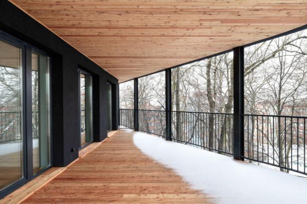 Eine schneebedeckte Holzterrasse mit Blick auf Bäume im Winter.