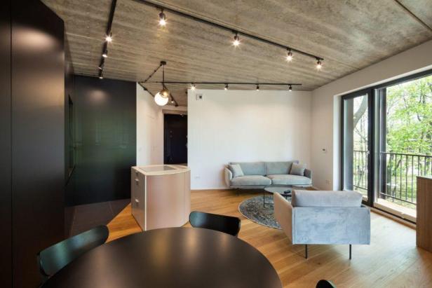 Ein modernes Wohnzimmer mit grauen Möbeln und einem Betonfußboden.