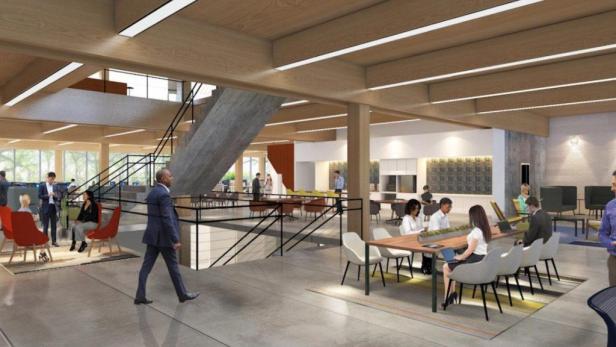 Ein Großraumbüro mit mehreren Personen, Tischen und Stühlen.