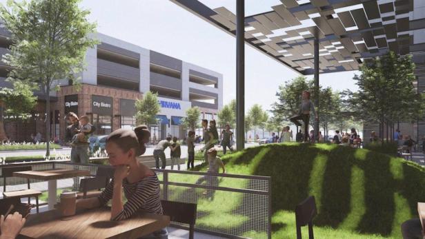 Eine belebte städtische Szene mit Menschen in einem Café und auf einer begrünten Fläche.