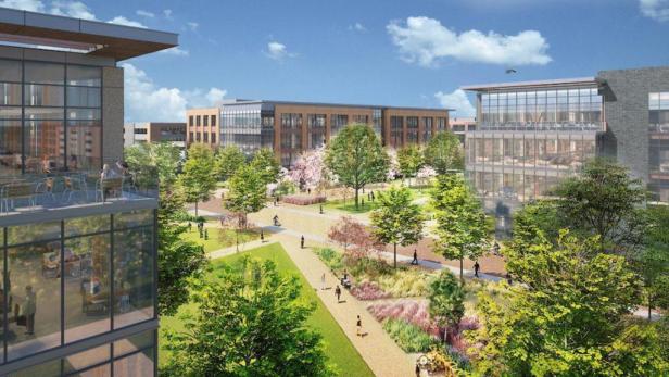 Eine parkähnliche Anlage zwischen Bürogebäuden mit Menschen auf Wegen.