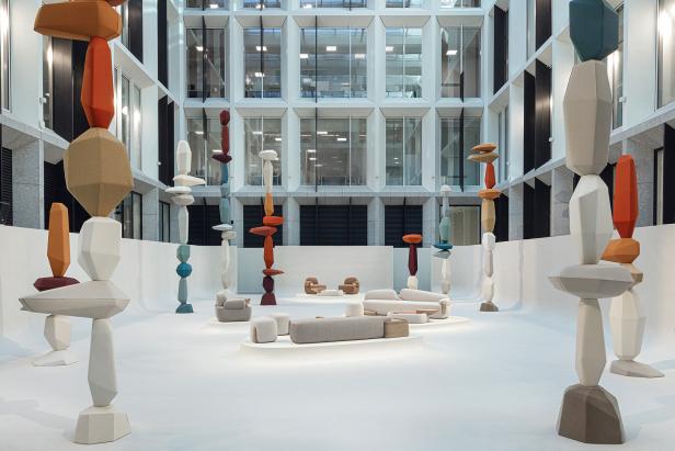 In einem Atrium stehen abstrakte, farbige Skulpturen und moderne Sitzmöbel.