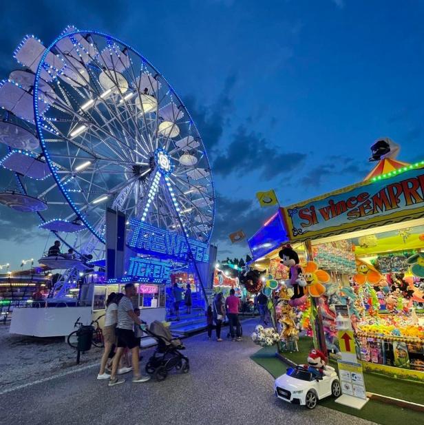 Ein beleuchtetes Riesenrad und ein Spielstand mit Plüschtieren auf einem Jahrmarkt.