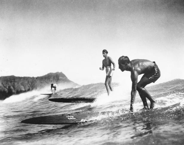 Drei Männer surfen auf ihren Brettern im Meer.