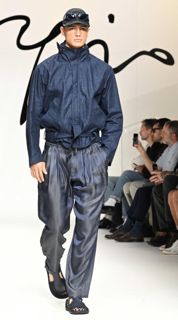 Ein Model präsentiert Sandalen und ein Outfit von Giorgio Armani.