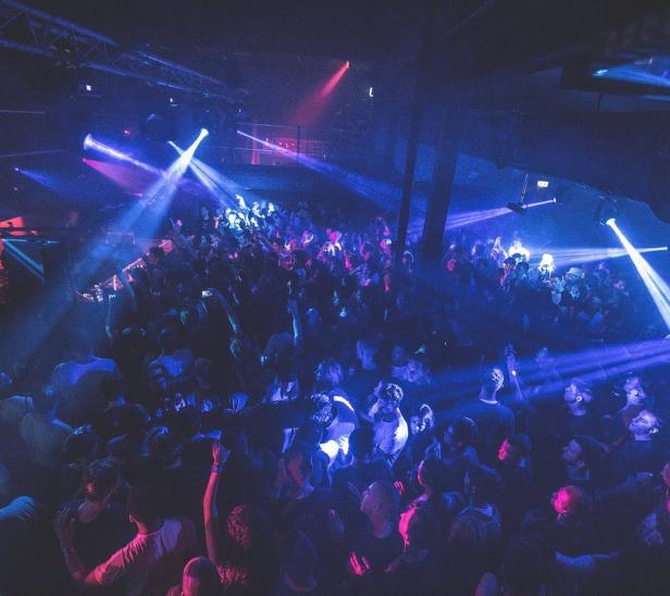 Eine Menschenmenge tanzt in einem Nachtclub unter blauem und rotem Licht.