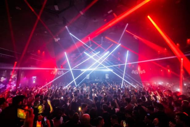 Eine große Menschenmenge feiert in einem Nachtclub mit roter und weißer Laserbeleuchtung.