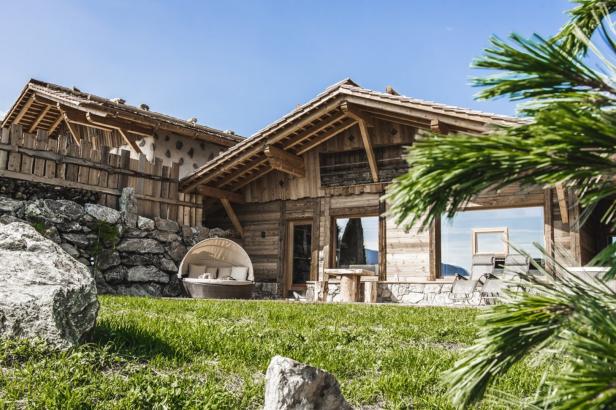 Ein Holzhaus mit einem gepflegten Garten und einem runden Liegebett im Freien.