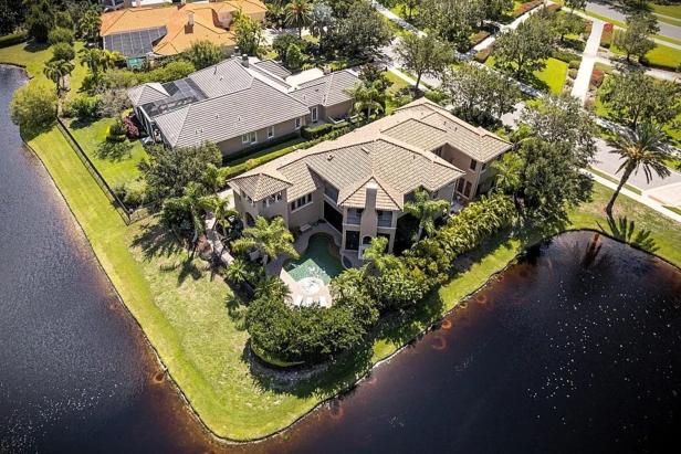 Luftaufnahme eines großen Hauses mit Pool an einem See.