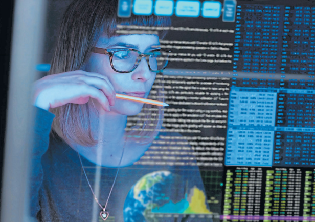 Eine Frau mit Brille betrachtet einen Bildschirm mit Daten und Code.