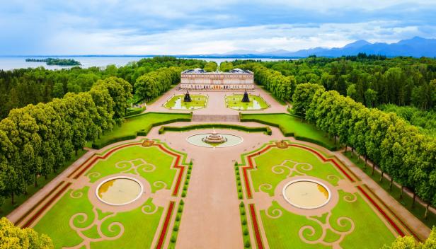 Luftaufnahme von Schloss Herrenchiemsee mit seinem weitläufigen Garten und den umliegenden Wäldern.