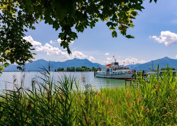 Ein Ausflugsschiff liegt an einem Steg auf dem Starnberger See vor den Alpen.
