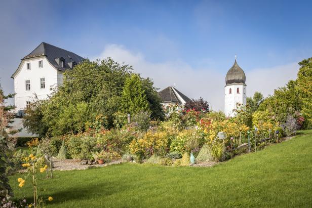 Ein Schlossgarten mit einem Turm und vielen bunten Blumen.