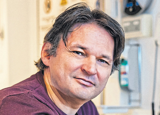 Porträt eines Mannes mit dunklen Haaren und einem weinroten T-Shirt.