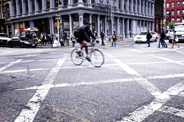 Ein Radfahrer überquert eine belebte Straße in einer Stadt.
