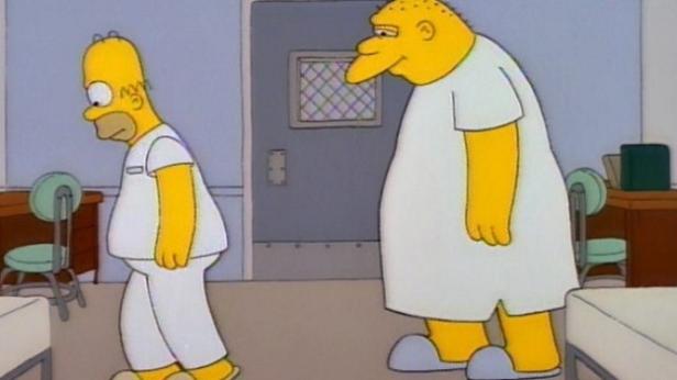 Homer Simpson und ein anderer Mann in einem Krankenhauszimmer.